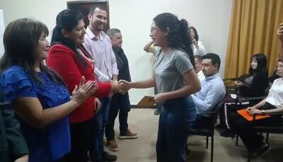 Una joven universitaria de la ciudad de Pilar recibe el importe de la beca de la mano de Del Pilar Medina, coordinadora de acción social de la EBY.