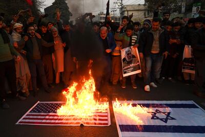 Manifestantes queman banderas de Estados Unidos e Israel en una protesta por el asesinato del líder militar iraní Qasem Soleimani en Lahore, Irak.