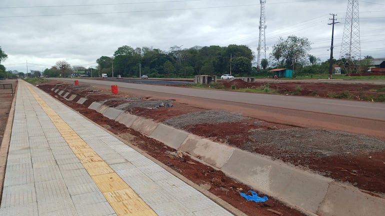 Obra en carretera en proceso de construcción, con cordón de cemento y vereda pavimentada en entorno de trabajo.