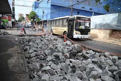 Ómnibus Nandutí navega entre piedras en una calle de Asunción, con un letrero de advertencia visible en el primer plano.