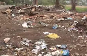 Terreno baldío en Itá Pytã Punta cubierto de basura y escombros, con vegetación escasa alrededor y sin personas presentes.