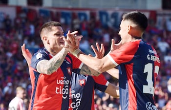 Futbolistas de Cerro Porteño celebrando, con camisetas rojas y azules, gestos de alegría y una multitud animada de fondo.