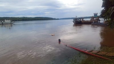 Ambiente acuático en Itapúa, con barcos en el río y vegetación inundada por el agua tranquila bajo un cielo nublado.