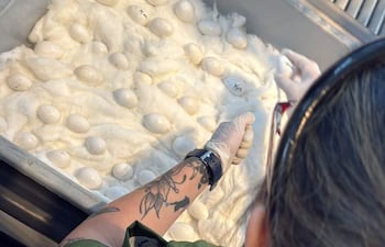 Una persona con tatuaje en el brazo y camiseta verde manipula huevos en laboratorio, usando guantes y con huevos sobre algodón.