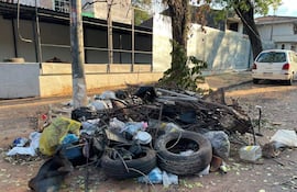 Montículo de basura en la calle, compuesto por neumáticos y bolsas plásticas, sin personas presentes.