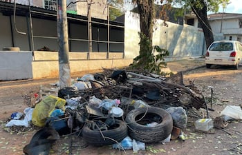 Montículo de basura en la calle, compuesto por neumáticos y bolsas plásticas, sin personas presentes.