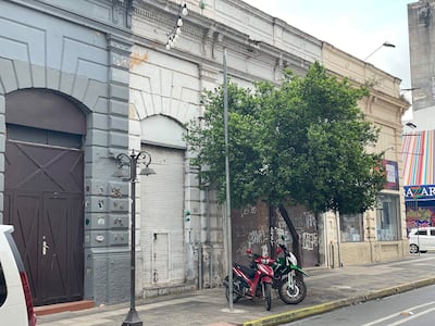 Calle vacía en Asunción con edificios viejos, árbol a la derecha y dos motocicletas estacionadas.