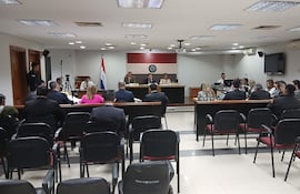 Mikhaela Rolón Melgarejo en audiencia, vestida formalmente, leyendo carta a jueces mientras varios asistentes la observan con expresiones diversas.