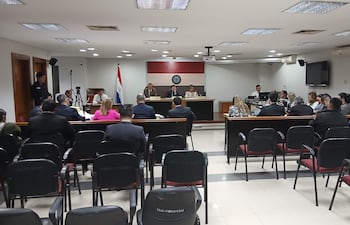 Mikhaela Rolón Melgarejo en audiencia, vestida formalmente, leyendo carta a jueces mientras varios asistentes la observan con expresiones diversas.