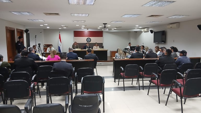 Mikhaela Rolón Melgarejo en audiencia, vestida formalmente, leyendo carta a jueces mientras varios asistentes la observan con expresiones diversas.