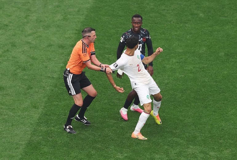 El árbitro Michael Oliver separa a Achraf Hakimi tras encarar al canadiense Richie Laryea, durante el friccionado primer tiempo.