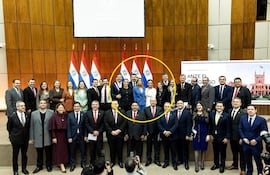 Santiago Peña en traje oscuro sonríe, rodeado de legisladores en un ambiente institucional con emblemas paraguayos.