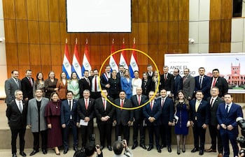 Santiago Peña en traje oscuro sonríe, rodeado de legisladores en un ambiente institucional con emblemas paraguayos.
