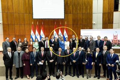 Santiago Peña en traje oscuro sonríe, rodeado de legisladores en un ambiente institucional con emblemas paraguayos.