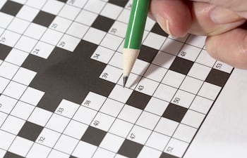 Una persona completa un cucrigrama con un lápiz verde