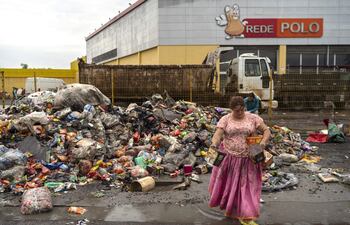 Una mujer recoge productos frente a un supermercado afectado por las inundaciones, en el municipio de São Leopoldo, en Rio Grande do Sul (Brasil). La aparición de casos y al menos cinco muertes por leptospirosis, una enfermedad bacteriana comúnmente transmitida por las ratas, preocupa a las autoridades tras las inundaciones.