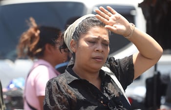 Una mujer se protege la cara para enfrentar la ola de calor que genera "temperaturas extremas" superiores a los 40 grados Celsius (° C) este martes, en San Salvador (El Salvador).
