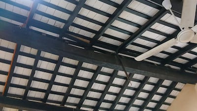 Techo de un pabellón con vigas de madera oscura y ventilador blanco, sin presencia de personas.
