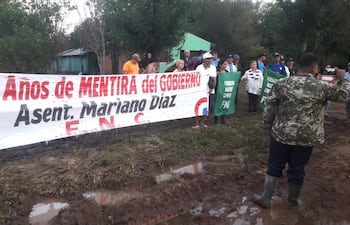 Grupo de personas sosteniendo un cartel que dice '4 Años de MENTIRA del GOBIERNO', en un entorno rural con terreno fangoso.