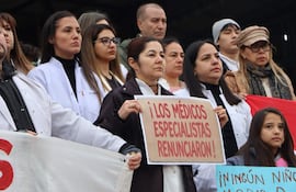 Grupo de médicos con batas blancas sostiene cartel de renuncia en Caacupé, mostrando expresiones serias y preocupadas.