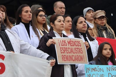 Grupo de médicos con batas blancas sostiene cartel de renuncia en Caacupé, mostrando expresiones serias y preocupadas.