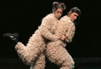 Paola Irún y Guadalupe Lobo en trajes esponjosos y claros, entrelazadas en el escenario oscuro durante una actuación.