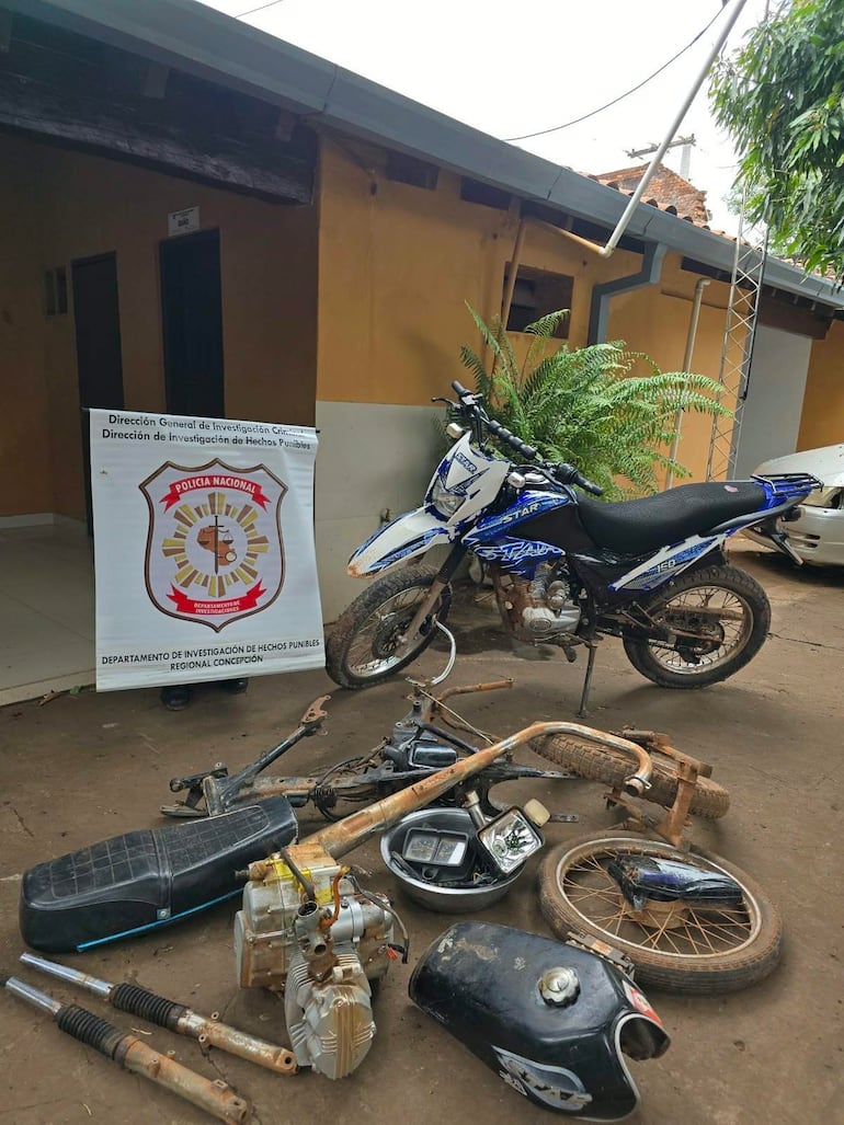 Escena de una investigación policial con motocicletas y cartel de la Policía Nacional en un ambiente urbano.