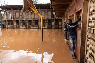 Dos personas unas un muro para cruzar una zona inundada en Nairobi, Kenia, el miércoles.