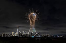Gran trofeo iluminado en el cielo nocturno sobre un paisaje urbano lleno de edificios modernos.