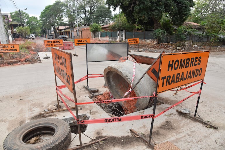 Escena urbana en San Pablo con señales de advertencia y un tubo de concreto volcado en una calle en obras.