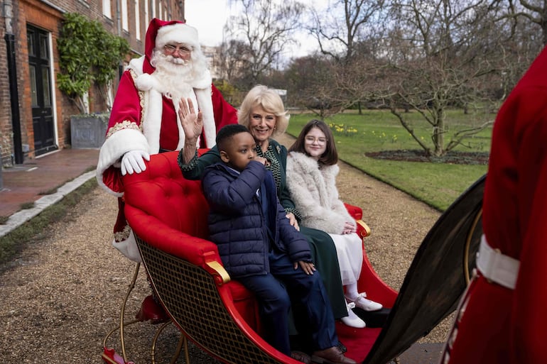 Camilla paseando feliz en un trineo con Samuel y Myla en los jardines de Clarence House. (Aaron Chown / POOL / AFP)