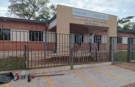 Tres personas de pie cerca de la entrada de la USF La Victoria, uno de los hombres conversando y la mujer observando, con elementos de limpieza visibles.