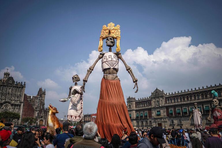 Personas observan enormes estatuas en el Zócalo de la Ciudad de México durante las celebraciones anuales del Día de Muertos el 2 de noviembre de 2025.