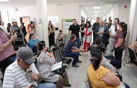 Isaías Ricardo Fretes y otros en la Unidad Sanitaria, con atmósfera de espera y diálogo entre médicos y pacientes.