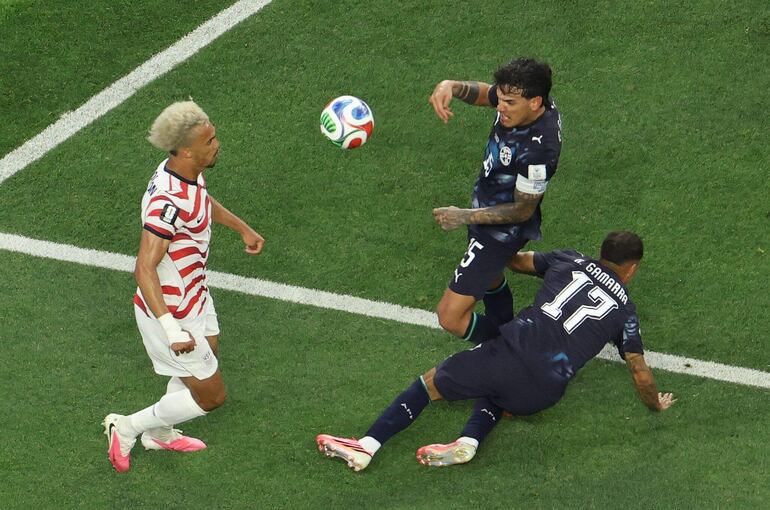 El defensor de Estados Unidos Antonee Robinson (izq.) lucha por el balón con el defensor de Paraguay Gustavo Gómez (c) y el mediocampista Alejandro Romero Gamarra durante el partido de fútbol del Grupo D de la Copa Mundial 2026 entre Estados Unidos y Paraguay en el Los Angeles Stadium en Inglewood.