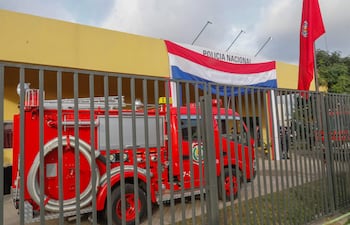 Edificio amarillo de la Policía Nacional con bandera paraguaya y camión de bomberos rojo estacionado.