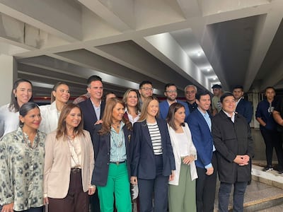 Soledad Núñez en blusa blanca, rodeada de su equipo sonriente, en un ambiente cerrado y formal.