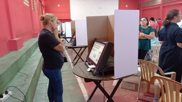 Una mujer se queda mirando la urna electrónica, en el local de la seccional de Villa Elisa porque se le trabó el boletín de voto.