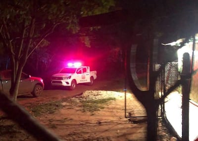 Camioneta de policía con luces intermitentes en un camino de tierra rodeado de árboles, sin personas visibles.