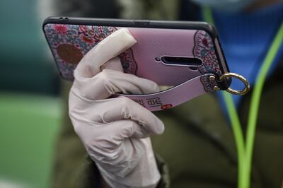 Una mujer con guantes sostiene un teléfono celular.