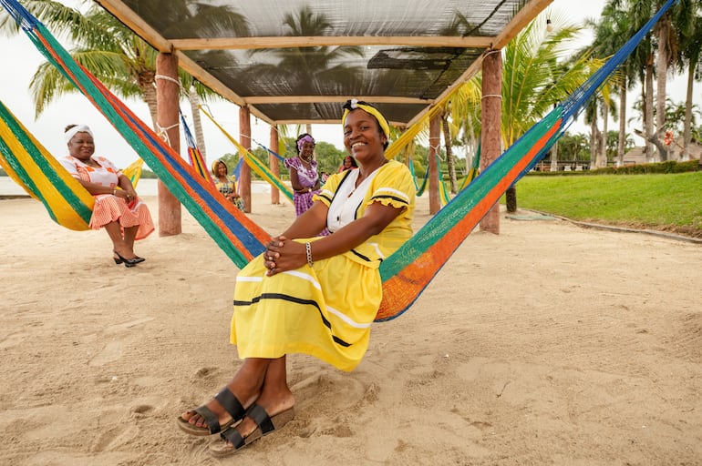 Retrato de un grupo de mujeres garífunas sentadas en hamacas con vestidos típicos de Livingston, Guatemala.