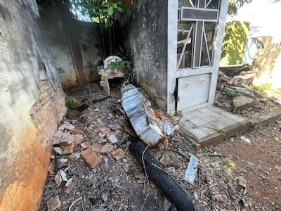 Estructura funeraria deteriorada rodeada de escombros y vegetación en un ambiente de abandono.