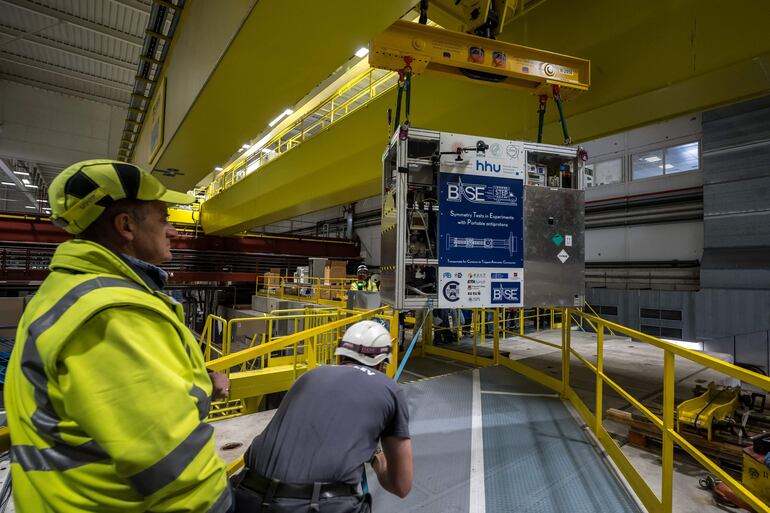 Un dispositivo portátil de trampa de Penning criogénica especialmente diseñado, cargado con una nube de 92 antiprotones, es transferido a un camión durante una prueba de conducción exitosa del primer sistema de transporte de antimateria del mundo, realizada por el experimento BASE-STEP del CERN, que trasladó antiprotones por carretera a través del sitio principal de la organización, en Meyrin, cerca de Ginebra, el 24 de marzo de 2026.