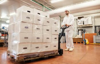 Trabajador de una industria cárnica transporta cajas con carne para exportación