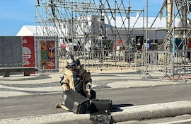 Fotografía distribuida por la Policía Civil de Río de Janeiro que muestra a un agente revisando una granada de mano encontrada en la playa de Copacabana, en Río de Janeiro, Brasil.