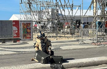 Fotografía distribuida por la Policía Civil de Río de Janeiro que muestra a un agente revisando una granada de mano encontrada en la playa de Copacabana, en Río de Janeiro, Brasil.