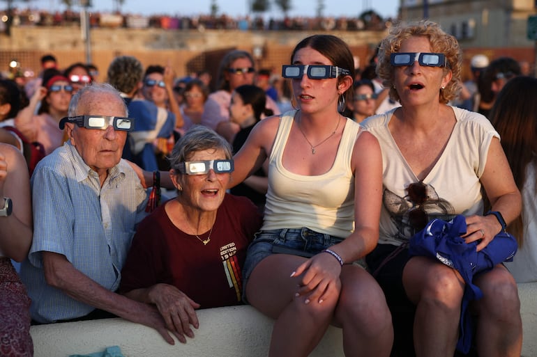 Personas reaccionan mientras observan el eclipse solar total desde el puerto de Tarragona, en el noreste de España, el 12 de agosto de 2026.