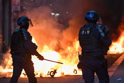Miembros de las Compañías Republicanas de Seguridad (CRS) de Francia permanecen frente a un incendio en la calle Faubourg du Temple, mientras estallan enfrentamientos en la plaza de la República tras una manifestación no autorizada en el centro de París, el 18 de octubre de 2026, un día después de las protestas a nivel nacional contra el «alto costo de la vida».