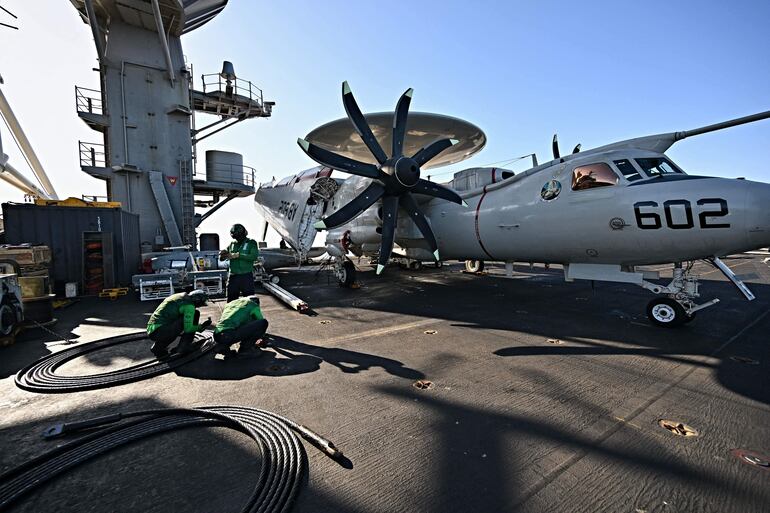 Miembros de la tripulación del portaaviones de propulsión nuclear estadounidense USS Harry S. Truman (clase Nimitz) trabajan en un avión de alerta temprana y control aerotransportado (AWACS) Grumman E-2 Hawkeye, en la cubierta de vuelo del buque, durante la actividad de vigilancia de la OTAN NEPTUNE SHIELD 2022 (NESH22) en el Mediterráneo oriental. (archivo)
