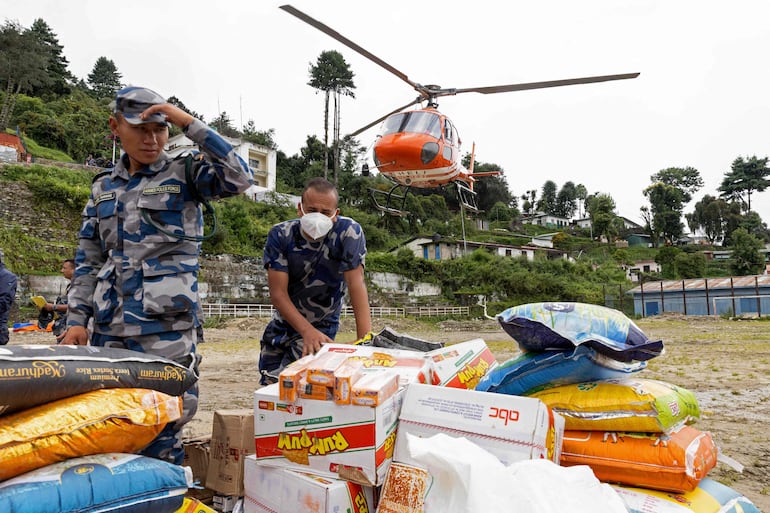 Personal de la Fuerza de Policía Armada (APF) de Nepal carga suministros de ayuda para los damnificados por las inundaciones en un helicóptero en Dhunche Bazaar, en el distrito nepalí de Rasuwa.